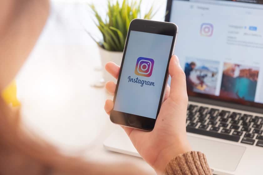 Junge Frau hält Smartphone in der Hand und macht mit Chingstars Instagram Marketing